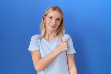 Kafkasyalı genç bir kadın, günlük mavi tişört giyiyor. Neşeli, yüzünde bir gülümseme var. Yüzünde mutlu ve doğal bir ifade var. 