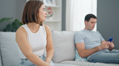 Kanepede sessizce oturan güzel çift evde akıllı telefon kullanıyor.