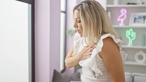 Young blonde woman suffering heart pain at home