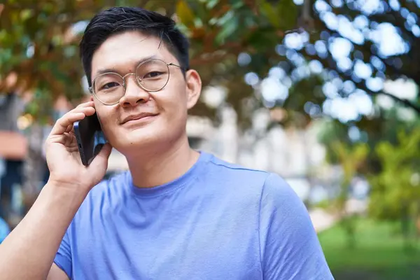 Young chinese man smiling confident talking on the smartphone at park