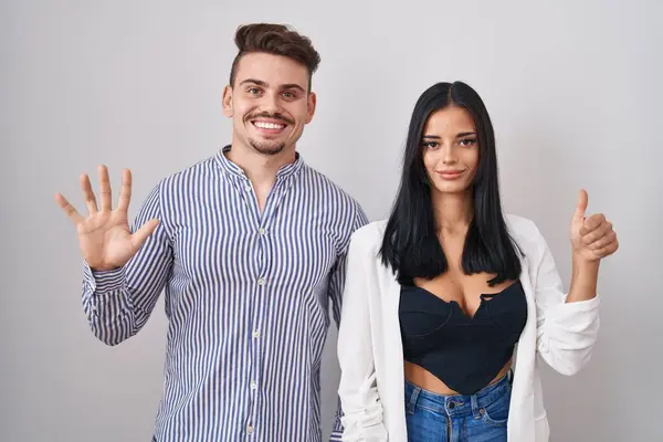 Young Hispanic Couple Standing White Background Showing Pointing Fingers Number — 图库照片