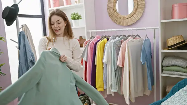 Young caucasian woman browsing clothes in a colorful, cozy wardrobe room