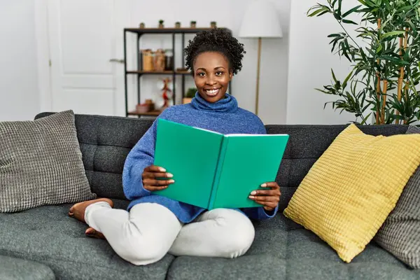 African American Woman Reading Book Sitting Sofa Home — ストック写真