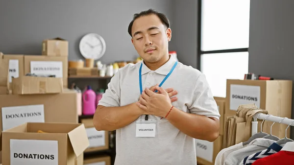 Handsome young chinese man, working tirelessly with heart in hands, volunteers at a local charity center in the community