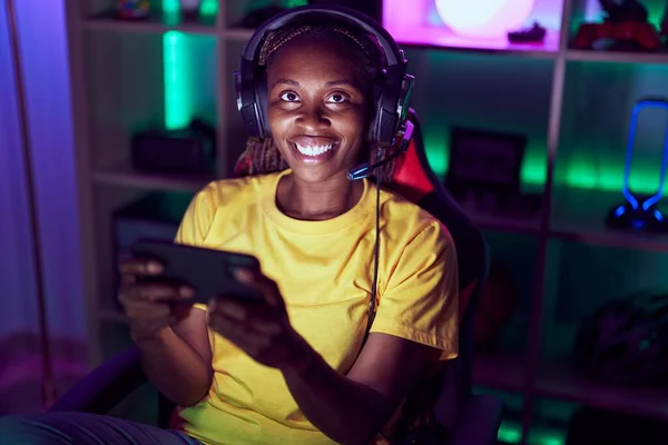 African american woman streamer playing video game using smartphone at gaming room