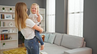 Neşeli anne güler yüzlü kızını kollarına alır, rahat evlerinde dimdik durur.