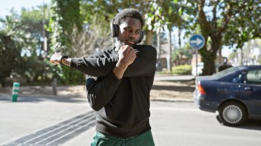 Afro-Amerikalı genç bir adam şehir sokaklarında kulaklıkları ve akıllı gözlükleriyle geziyor..