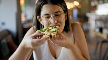 Genç ve güzel İspanyol kadın restoranda lezzetli pizzalar yiyor.