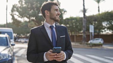 Yakışıklı İspanyol takım elbiseli adam Sunny City caddesinde akıllı telefon kullanıyor.