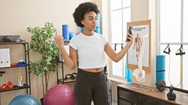 Afrikalı Amerikalı bir kadın spor salonunda arka planda egzersiz ekipmanıyla selfie çekiyor..