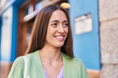 Young beautiful hispanic woman smiling confident looking to the side at street