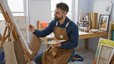 Kendine güvenen mutlu İspanyol genç adam, sanat stüdyolarında çalışan ressam. 