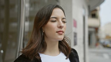 Sakince gülümseyen sakin bir İspanyol kadın şehir sokaklarında kendine güveni ve güzelliği yayıyor..