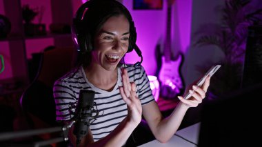 Genç ve güzel İspanyol kadın, oyun odasında akıllı telefon kullanıyor.