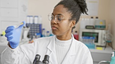 Bir laboratuarda test tüpünü inceleyen Afrikalı Amerikalı kadın bilim adamı..