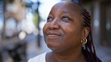 Kentsel aura, bu ciddi görünümlü Afro-Amerikan kadını bir şehir caddesinde, bakışları gökyüzüne yükselmiş, endişeli bir ifade taşımasına rağmen serin ve rahat bir yaşam tarzını somutlaştırıyor..