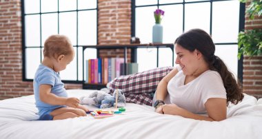Anne ve oğlu yatakta uzanıp yatak odasında oynuyorlar.