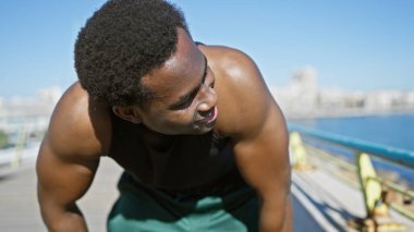 Genç bir Afrikalı Amerikalı açık deniz kenarında güneşli bir havada dinleniyor..