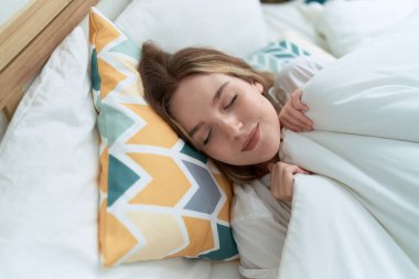 Beyaz bir kadın yatakta uzanıyor, yatak odasında uyuyor.