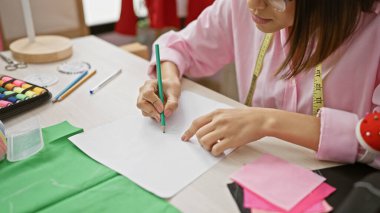 Yaratıcı bir atölyede tasarımcı kıyafetleri dikmeye odaklanmış bir kadın.