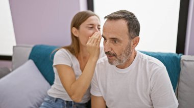 Evde, kanepede birlikte, sevgi dolu bir baba ve kız sırlarını paylaşıyor, rahat ve rahat yaşam tarzlarına güven ve mutluluk yayıyor.