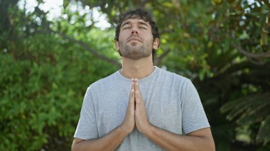 Genç, yakışıklı, sarışın, sakallı adam yaz kenti yoga egzersizinde denge ve özgürlük buluyor, güneş ışığında banyo yapıyor, gözleri meditasyon nefesi ve yansımasıyla kapalı.