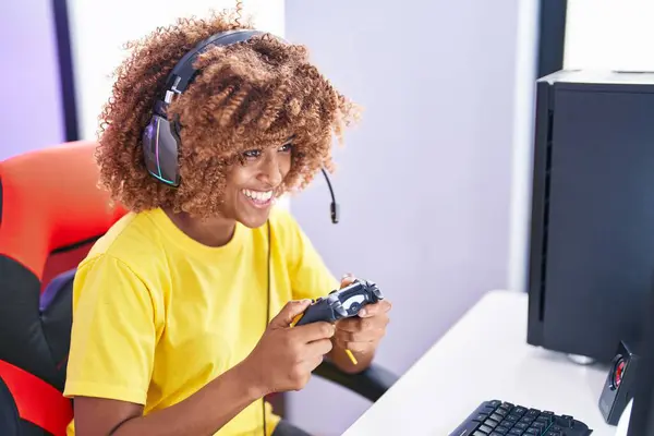 African american woman streamer playing video game using joystick at gaming room