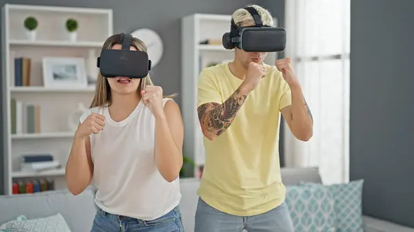 Beautiful couple playing boxing video game using virtual reality glasses at home