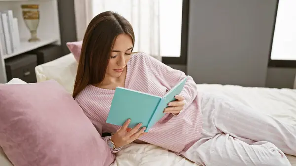 A woman reads a book in bed, portraying a cozy, relaxed bedroom with pillows and elegant decor.