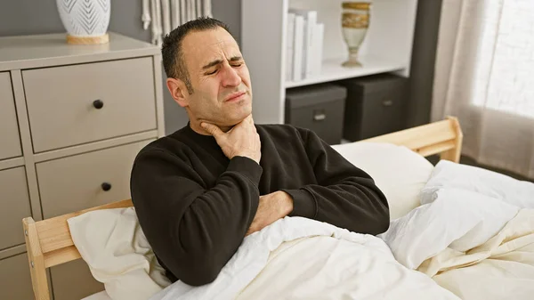 Hispanic Man Discomfort Sitting Bed Holding His Neck Modern Bedroom — Stock Photo, Image