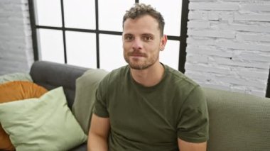 Evdeki kanepede oturan zeki genç adam, neşeli bir ifadeyle parmağını kaldırıyor, bir numaralı başarı fikrini sergiliyor, heyecanlı ve mutlu.!