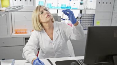 Orta yaşlı kadın bilim adamı modern bir laboratuvar ortamında bir örneği analiz ediyor.