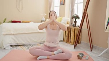 Huzurlu bir evde yoga yapan bir kadın meditasyon sırasında refahını ve huzurunu gösteriyor..