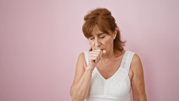 穿着衣服的中年妇女身体不舒服 感冒或支气管炎咳嗽 在粉红的背景下孤立无援 这是可悲的医疗保健情景 — 图库视频影像
