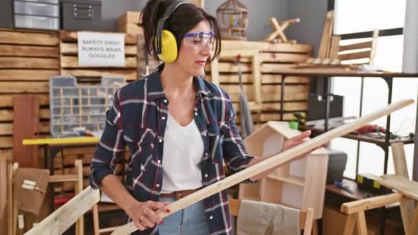 Dojrzała Kobieta Sprawdza Drewno Dobrze Wyposażonej Stolarni Nosząc Okulary Ochronne — Wideo stockowe