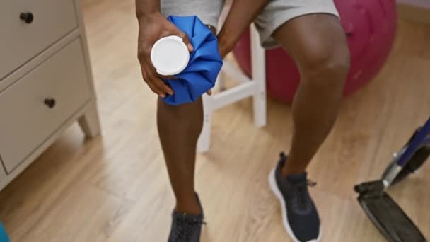 Hombre Afroamericano Clínica Fisioterapia Usando Bolsa Hielo Rodilla — Vídeos de Stock