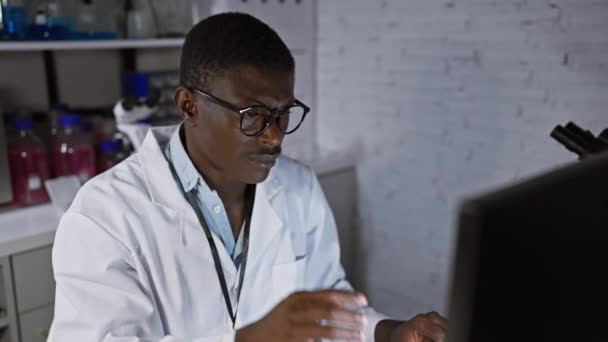 Африканский Мужчина Лабораторном Халате Анализирует Данные Компьютере Лабораторных Условиях — стоковое видео