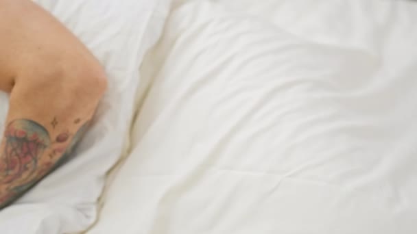 Татуированный Молодой Человек Мирно Спящий Белой Кровати Изображая Отдых Интерьер — стоковое видео