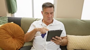 Evde online alışveriş için tablet ve kredi kartı kullanan olgun bir adam