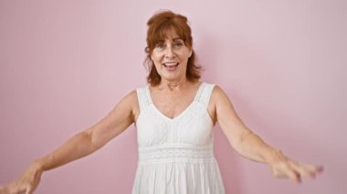 Pembe elbiseli, kendinden emin orta yaşlı bir bayan neşeli bir şekilde dokuz numarayı gösteriyor, parmaklarını izole bir arka planda gösteriyor..