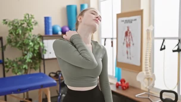 Ung Kvinna Klinik Håller Nacken Vilket Tyder Smärta Omgiven Rehabiliteringsutrustning — Stockvideo