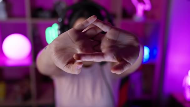 ヘッドフォンを持つ若いヒスパニック女性は 夜中に自宅でネオンライトのゲームルームで微笑む — ストック動画