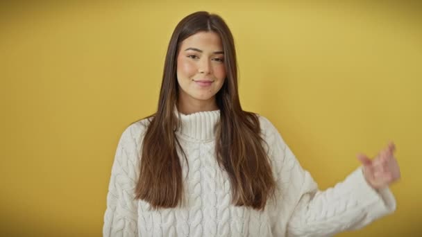 美しいセーターで自信を持って若いヒスパニック女性 孤立した黄色の背景の上に立って 手で明るく小さなサイズのサインをジェスチャーし 無限のカリスマで測定コンセプトを体現 — ストック動画