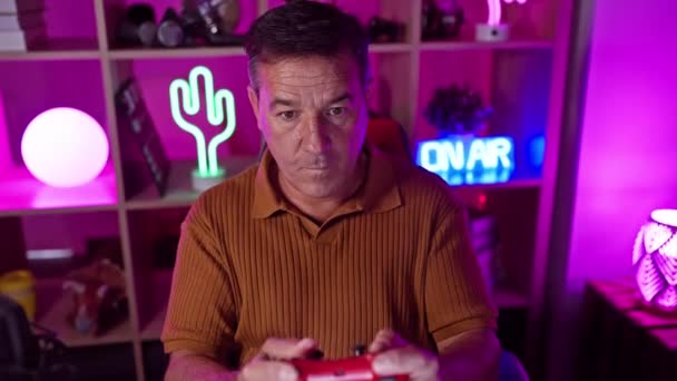 Reifer Mann Spielt Mit Einem Konsolencontroller Einem Lebhaften Neonbeleuchteten Spielzimmer — Stockvideo