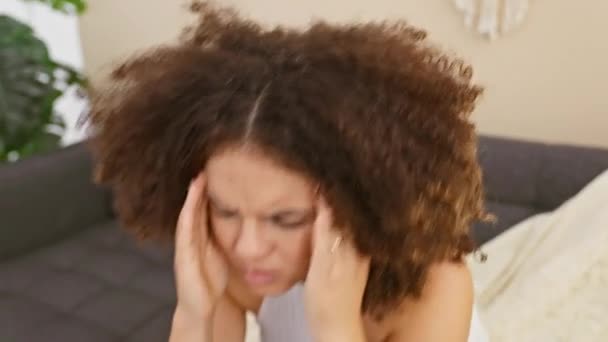 Обеспокоенная Молодая Латиноамериканка Вьющимися Волосами Держит Голову Сидя Диване Помещении — стоковое видео