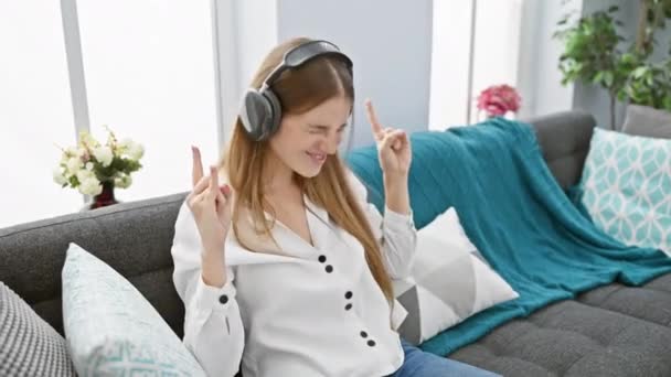Eine Fröhliche Frau Mit Kopfhörern Genießt Musik Auf Einem Sofa — Stockvideo