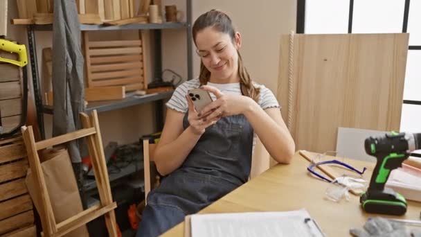Glimlachende Jonge Vrouw Met Smartphone Een Houtbewerkingsatelier — Stockvideo