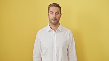 Mest olmuş genç İspanyol bir adam, kolları zaferle havada, başarıyı neşe ve zaferle kutluyor, izole edilmiş sarı bir arka plana karşı duruyor.