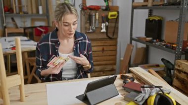 Atölyedeki genç kadın etrafında aletler ve tabletlerle Filipin pesolarını sayıyor..