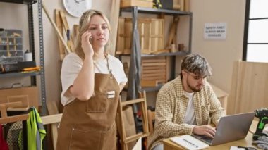 Telefonda konuşan bir kadın ve arka planda marangozluk aletleriyle atölyede dizüstü bilgisayarda çalışan bir adam..